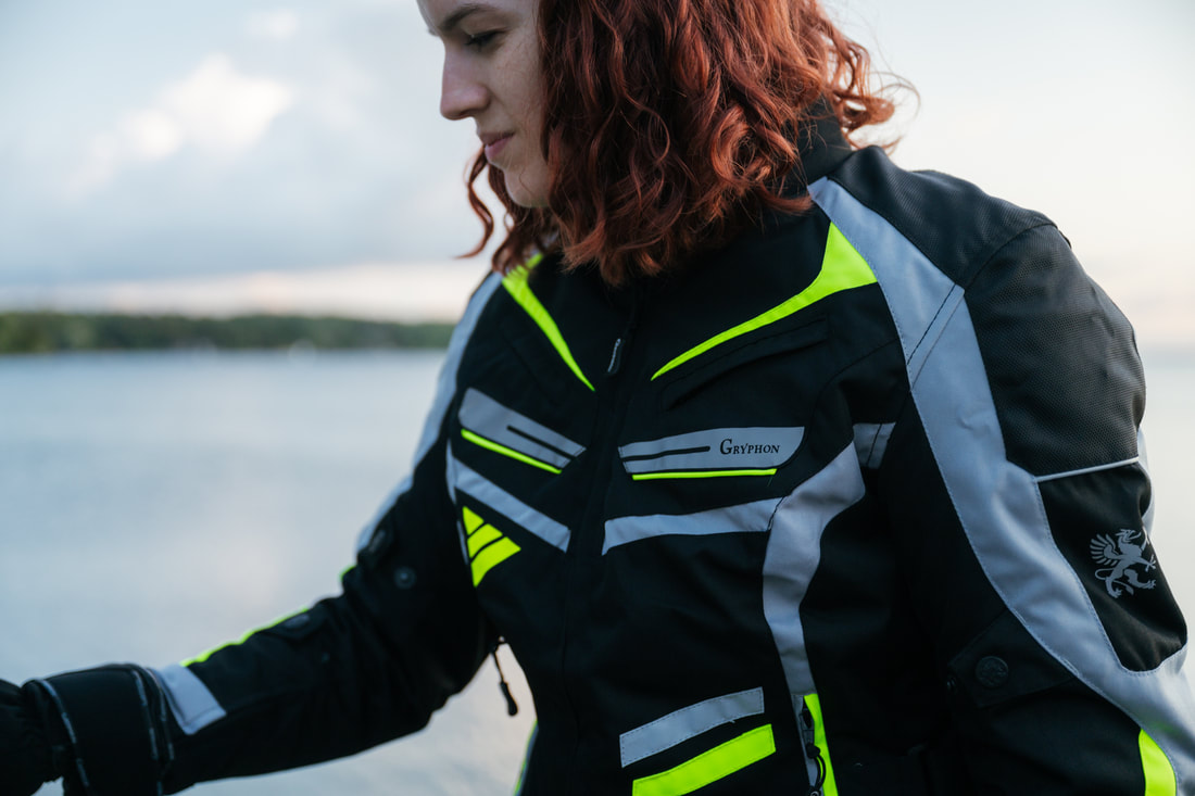 woman at the beach with red hair looking down wearing a gryphon motorcycle jacket