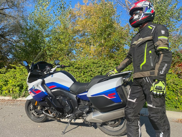 man standing beside his motorcycle wearing all gryphon motorcycle jacket, gryphon pants and gryphon gloves and a helmet 