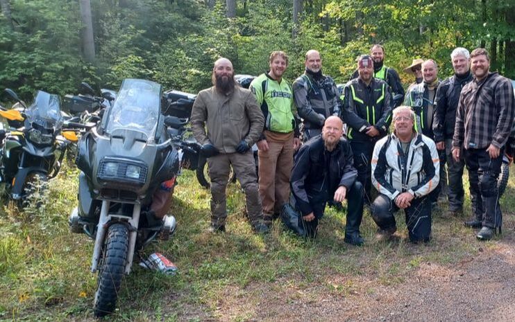 group of men with their motorcycles on a ride in the forest